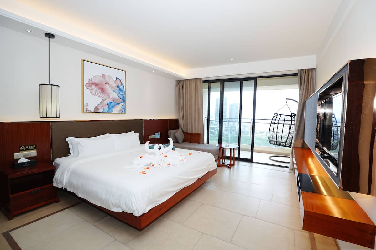 Una habitación de hotel moderna con una cama grande, un televisor de pantalla plana, un balcón con vistas a la ciudad y un cuadro en la pared.
