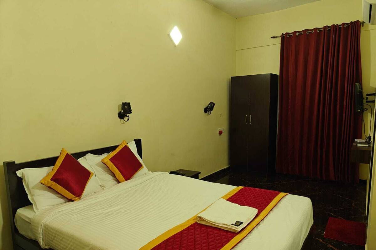 A hotel room with a bed, a wardrobe, and a red curtain.