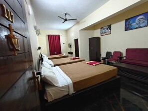 A hotel room with two beds, a ceiling fan, a red curtain, a wardrobe, and a painting on the wall. - Royal Parisian Residency (Pattukkottai)