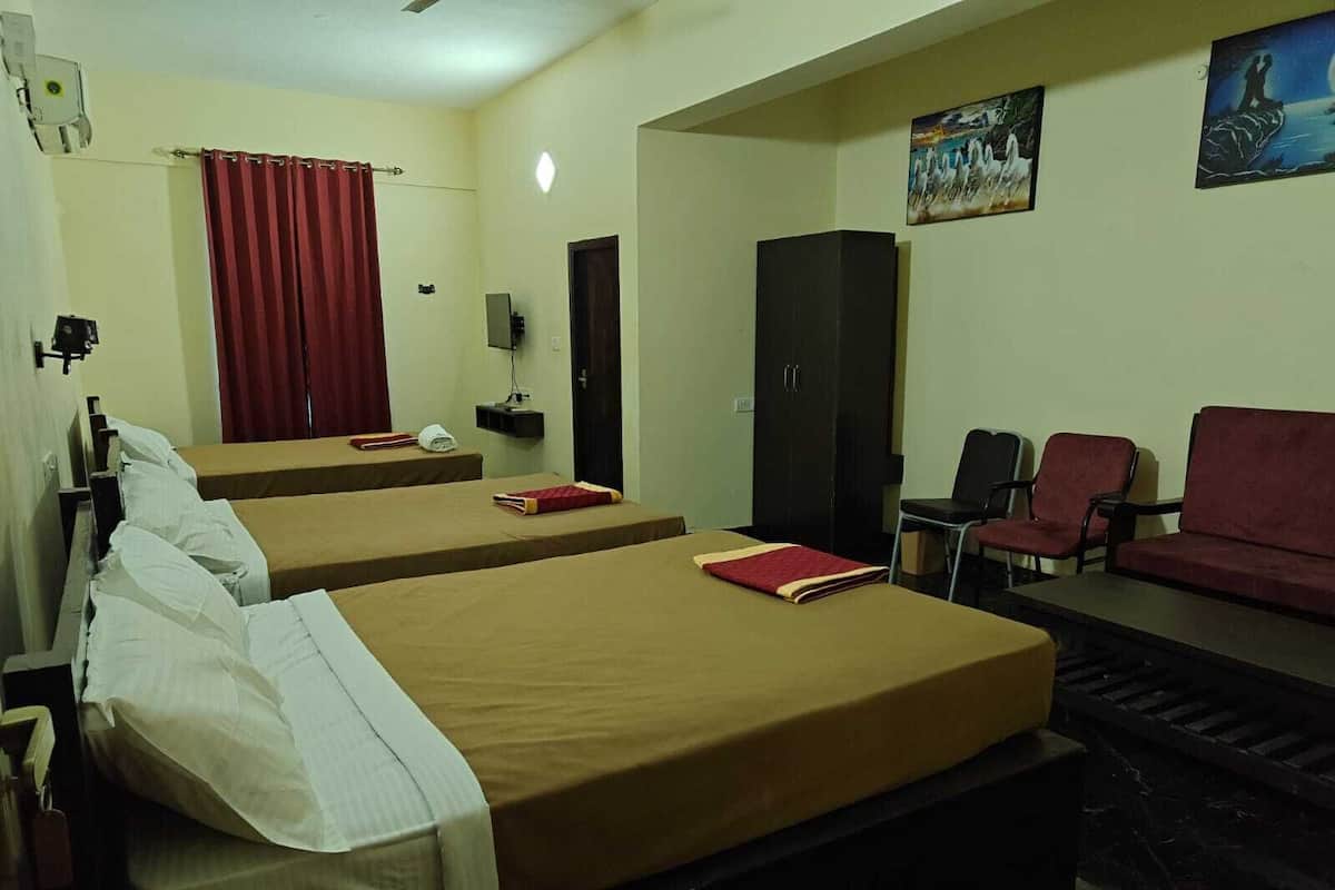 A hotel room with two single beds, a sofa, a desk, and a TV.
