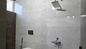 Een badkamer met een toilet, een douche en een emmer op de vloer.