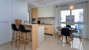 A modern kitchen with a central island, bar stools, and a dining table with chairs. - CH Enora Garden Doña Pepa (Ciudad Quesada) (Ciudad Quesada)
