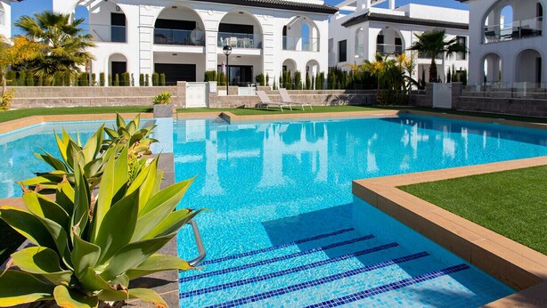 A swimming pool with clear blue water, surrounded by a well-maintained lawn and tropical plants. - CH Enora Garden Doña Pepa (Ciudad Quesada) (Ciudad Quesada)