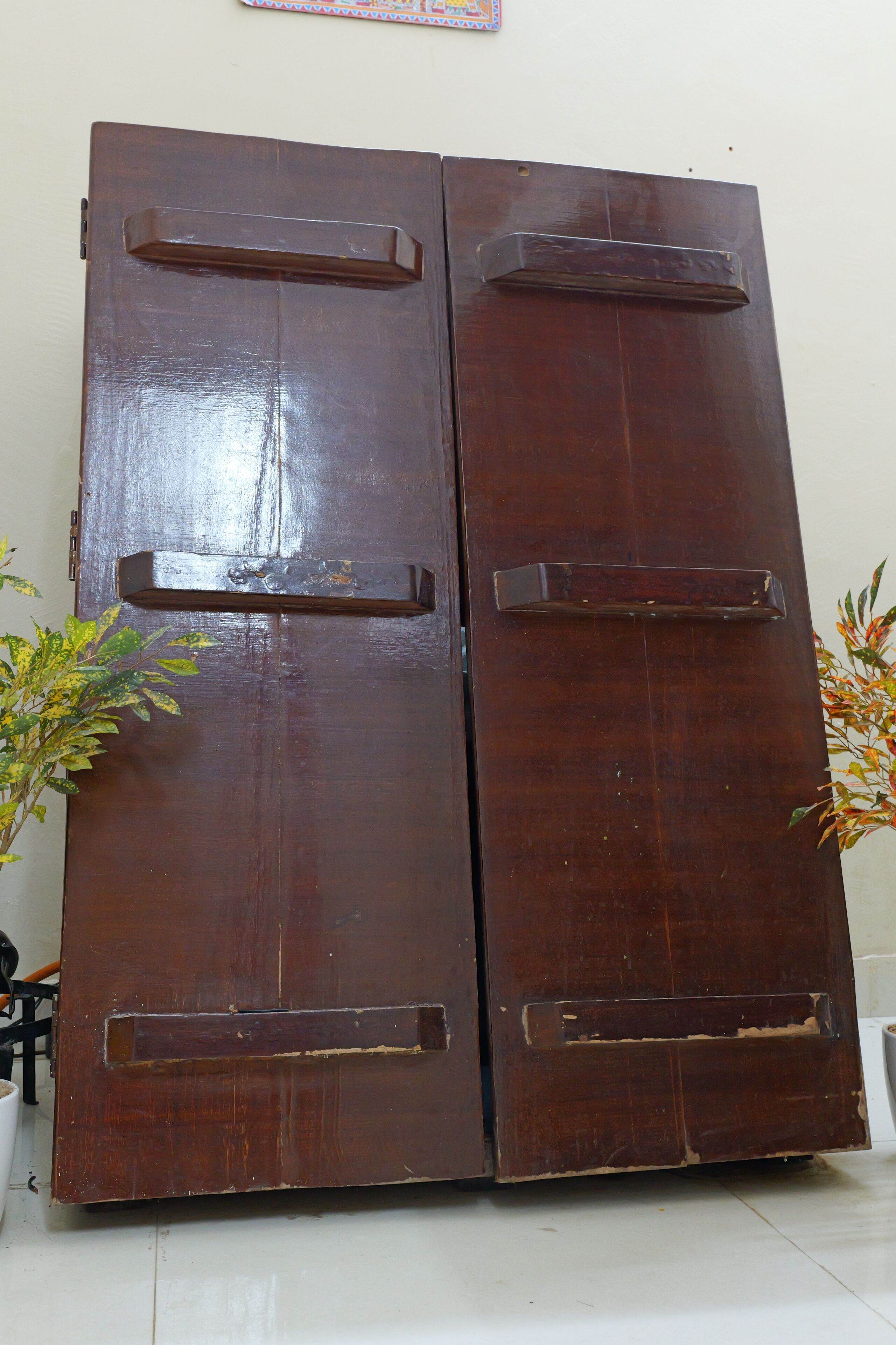A large wooden double door with two handles and a small rectangular window.