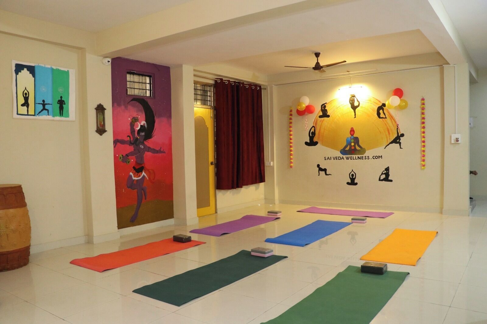 A yoga studio with mats, a mural, and wellness symbols on the wall.