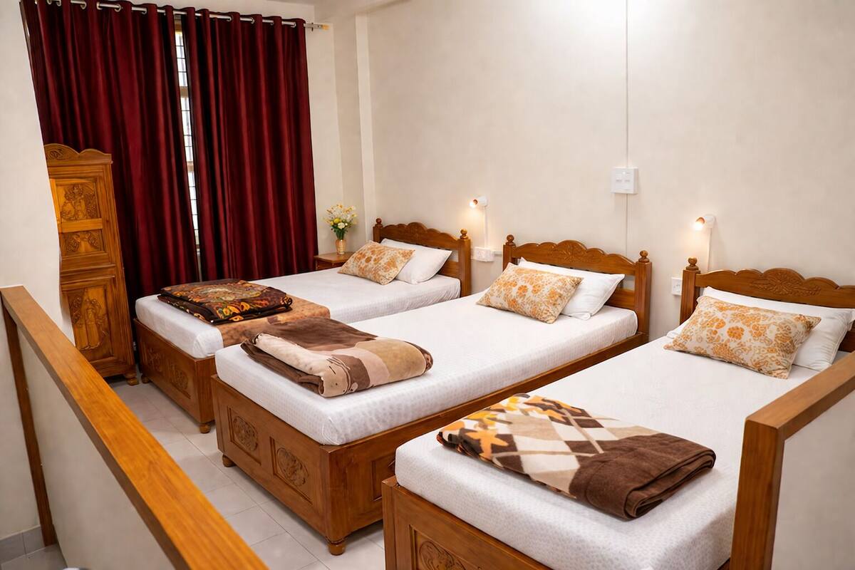 Quarto de hotel com três camas de madeira, um guarda-roupa de madeira e uma cortina vermelha.