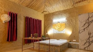 Een kamer met een bed, een ventilator, een tafel met een vaas en een muur met een zonontwerp.
