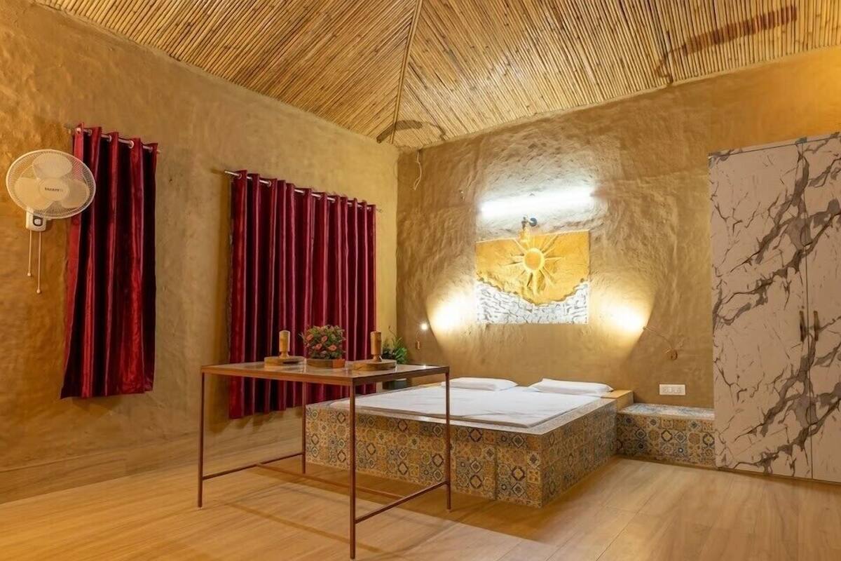 Quarto com uma cama, um ventilador, uma mesa com um vaso e uma parede com desenho de sol.