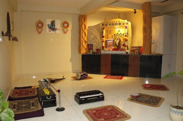 Una habitación con un pequeño santuario, instrumentos musicales y alfombras decorativas.