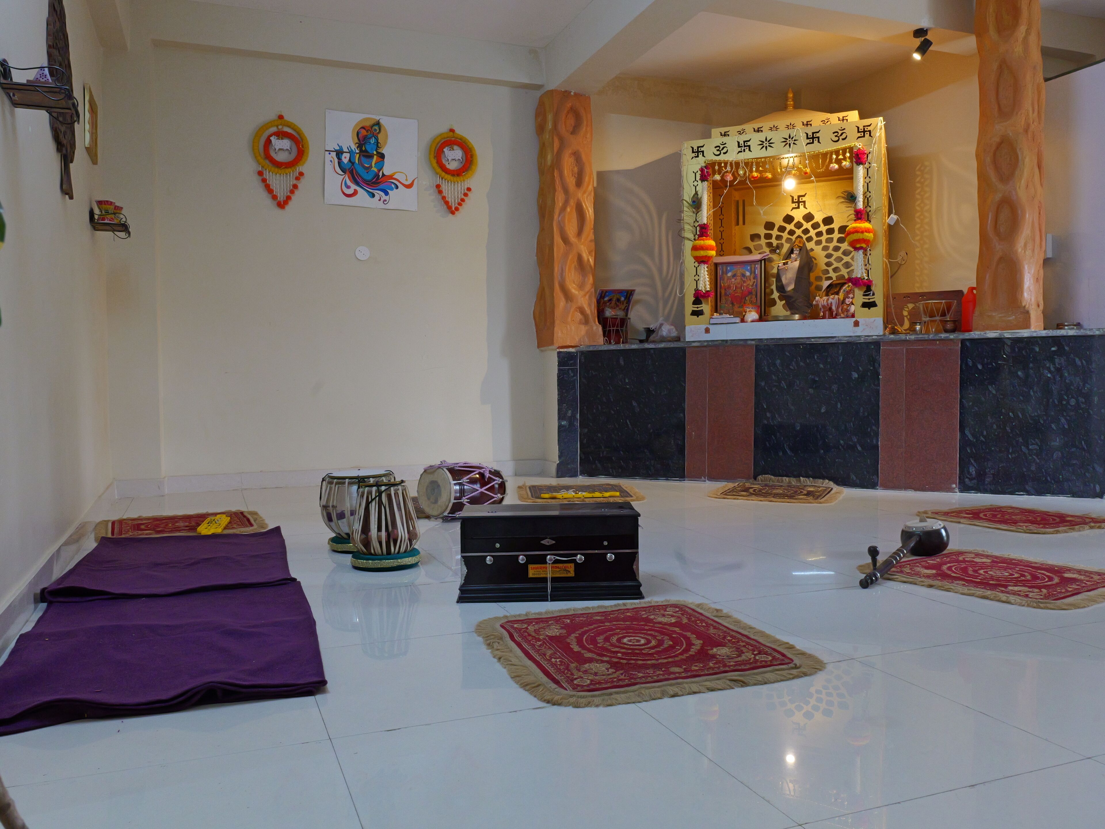 A room with a tiled floor, a small altar with religious items, and a few musical instruments.