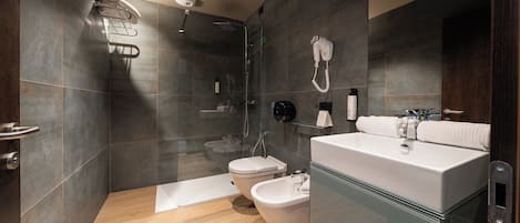 A modern bathroom with a glass-enclosed shower, a large mirror, and a vanity with a sink and towel rack.