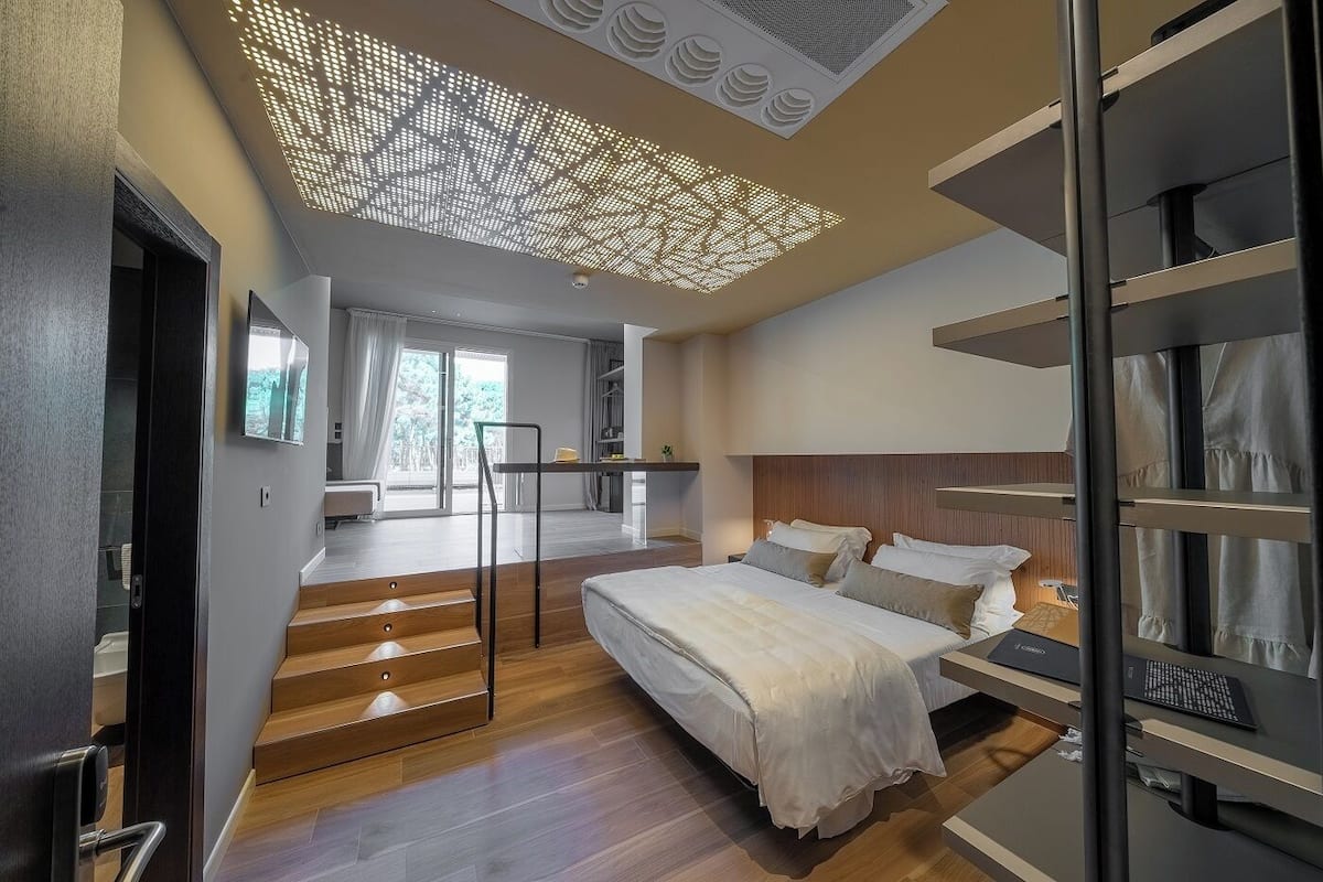 Un dormitorio moderno con una cama grande, un escritorio y una escalera que sube a un nivel superior.