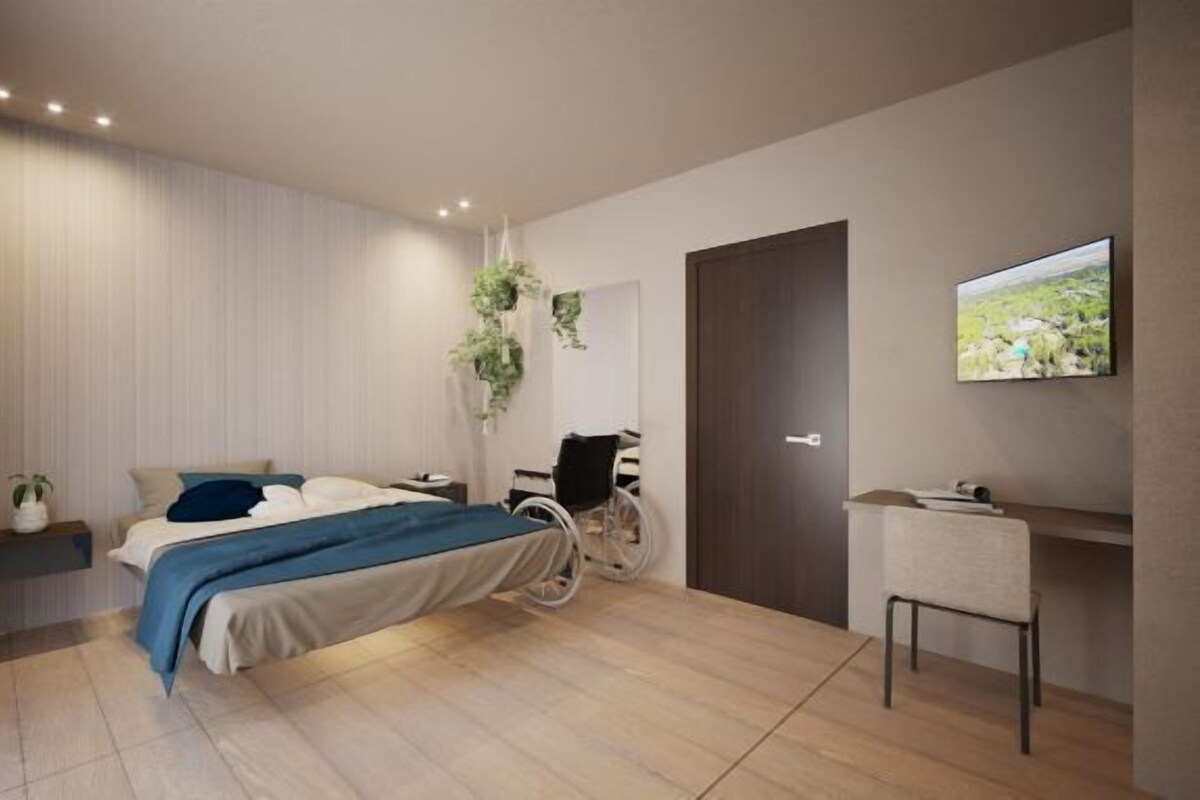 A modern bedroom with a bed, bedside table, chair, and a TV on the wall.