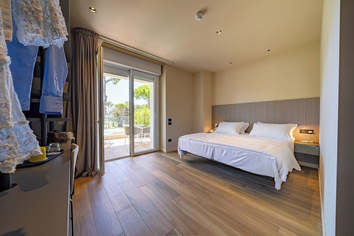 Un dormitorio con cama, mesita de noche, lámpara, puerta corrediza de vidrio que da a un espacio exterior y vistas al exterior.