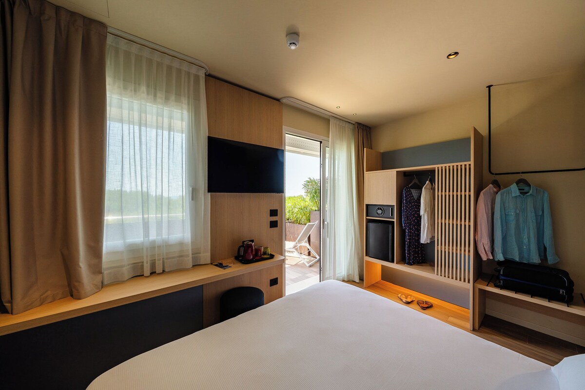 A hotel room with a bed, a desk, a TV, a wardrobe, and a balcony.