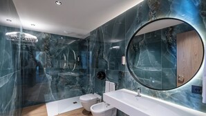 Un baño moderno con cabina de ducha de vidrio, tocador doble y un espejo grande.