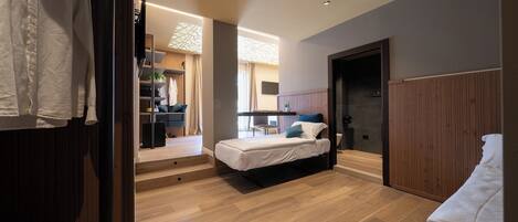 A modern bedroom with a bed, a desk, and a walk-in closet.
