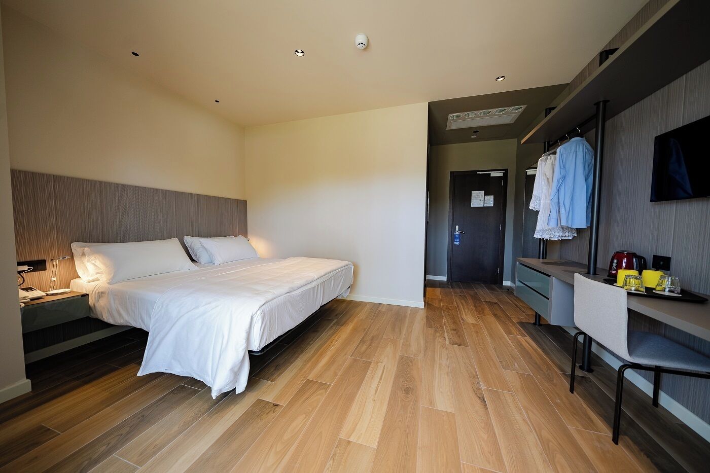 Habitación de hotel moderna con una cama grande, un escritorio con silla y un televisor de pantalla plana montado en la pared.