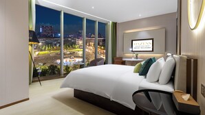 A modern hotel room with a large bed, a desk, and a view of a cityscape at night. - Chengdu Hazens Hotel (Chengdu)