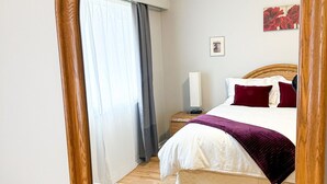 Ein Schlafzimmer mit einem hölzernen Bett, einem Nachttisch mit Lampe und einem großen Spiegel.