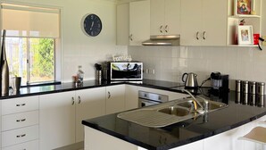 A modern kitchen with white cabinetry, a black countertop, a built-in oven, and a sink.