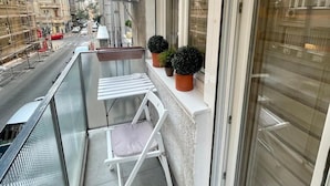 Een balkon met een witte stoel, een tafeltje en potplanten.