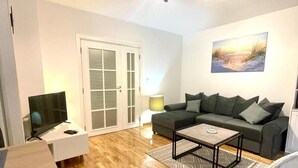 Een woonkamer met een bank, een salontafel, een televisie en een stoel.