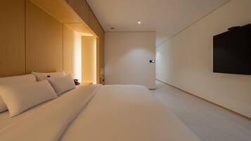 Une chambre d’hôtel moderne avec un grand lit, un mur recouvert de panneaux en bois et un téléviseur fixé au mur.