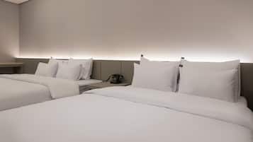 A hotel room with two beds, a bedside table, and a wall-mounted phone.
