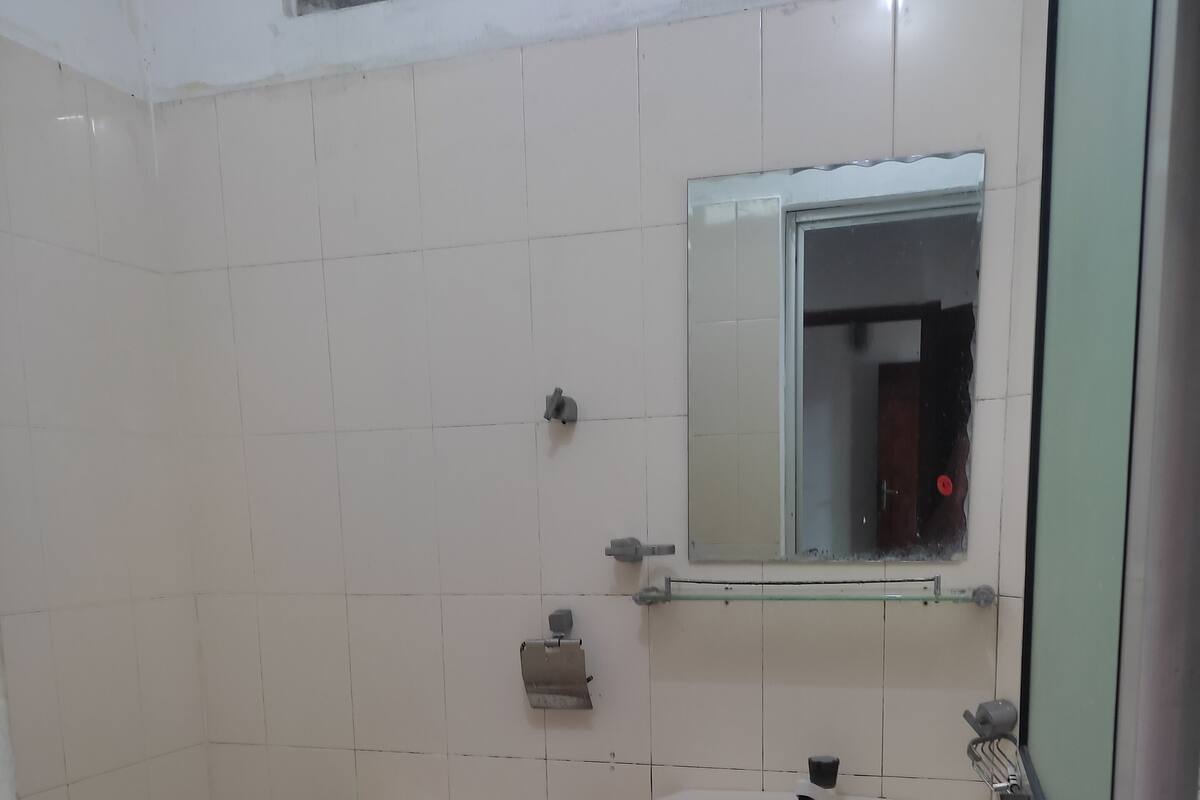 Une petite salle de bain propre, équipée de toilettes, d’un lavabo et d’un miroir.