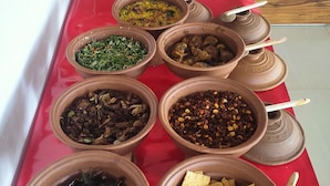 Une table de buffet présentant divers plats dans des pots et des bols en argile.