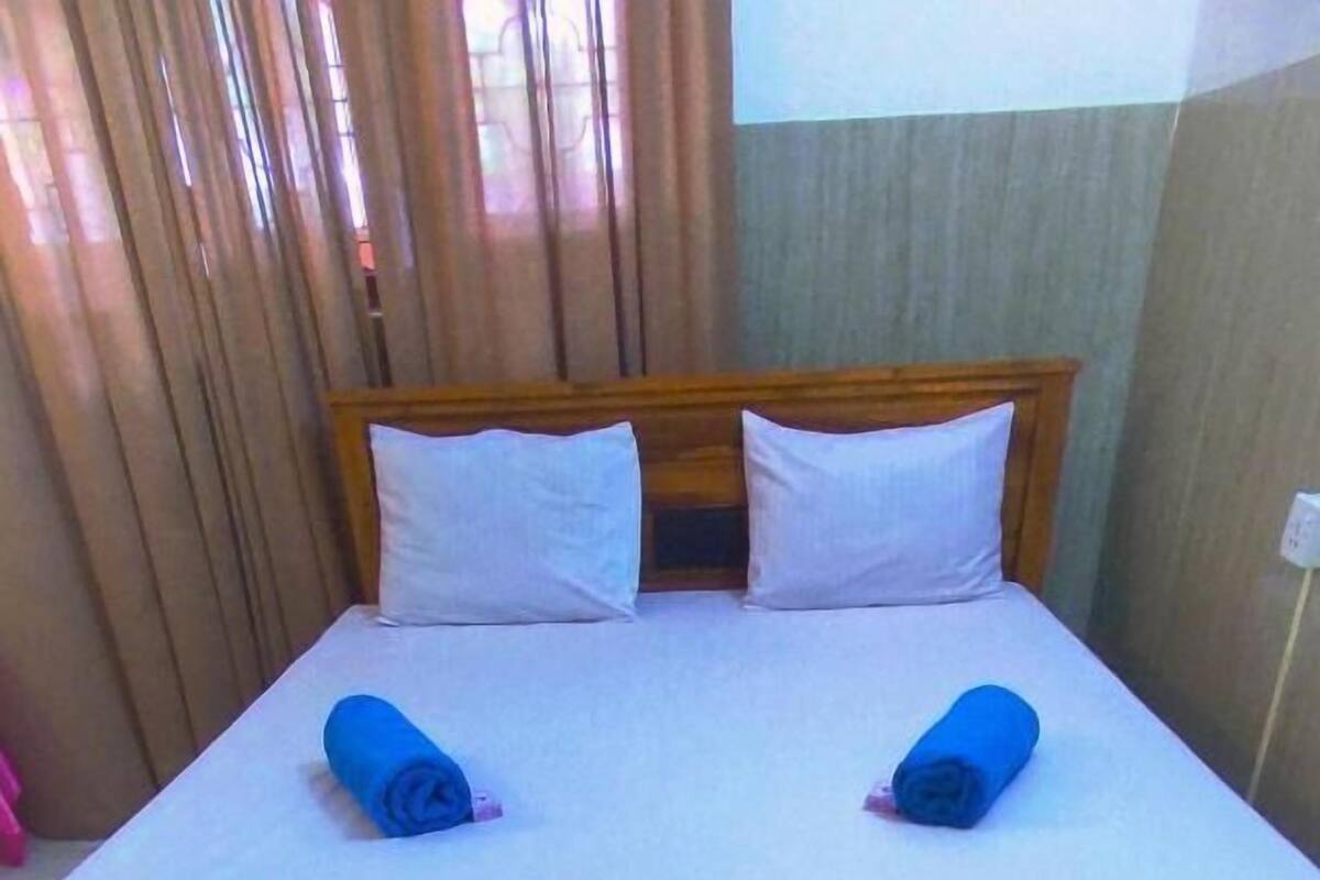 Un lit avec du linge de lit blanc et deux serviettes bleues enroulées.