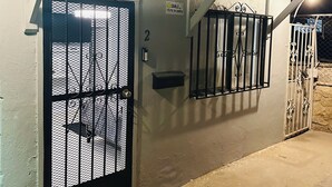 A gated entrance with a metal gate, a number '2' sign, and a small shelf. - Odriozola’s Vrbo Studio (El Paso)