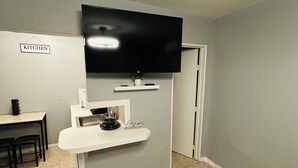 A compact kitchen area with a built-in TV, a small dining table, and a sign labeled "KITCHEN". - Odriozola’s Vrbo Studio (El Paso)