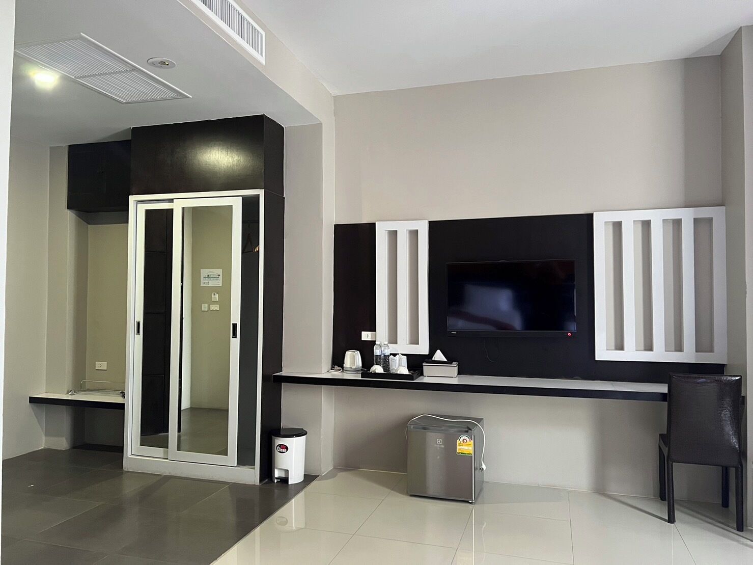 A modern kitchen with a built-in TV, a coffee machine, and a trash bin.
