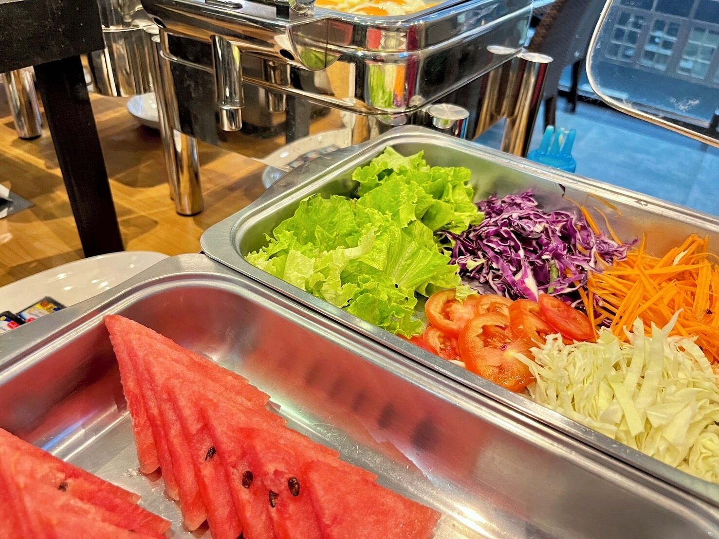 A buffet with various fresh vegetables including lettuce, tomatoes, and carrots.