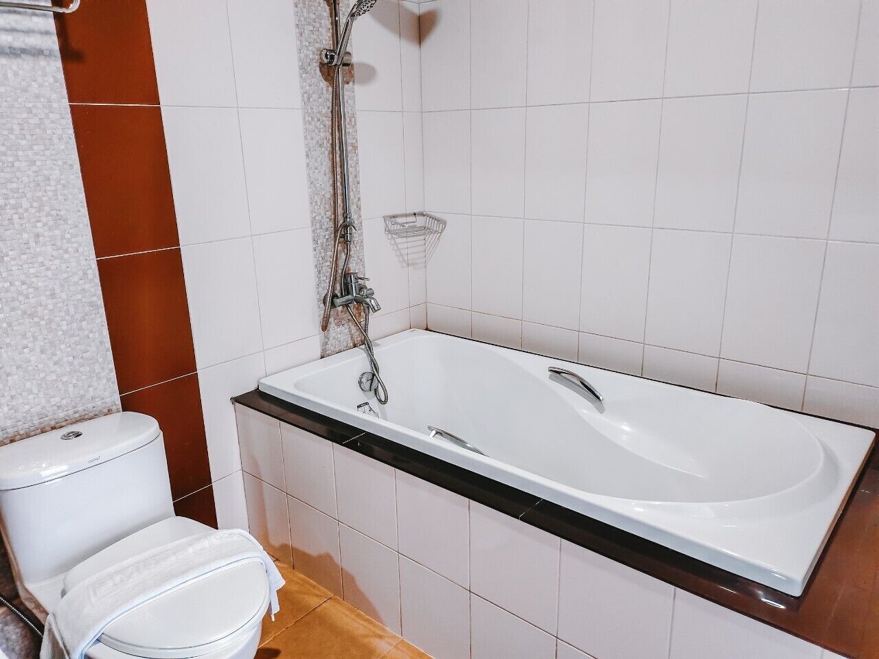 A bathroom with a white bathtub, a toilet, and a shower area.