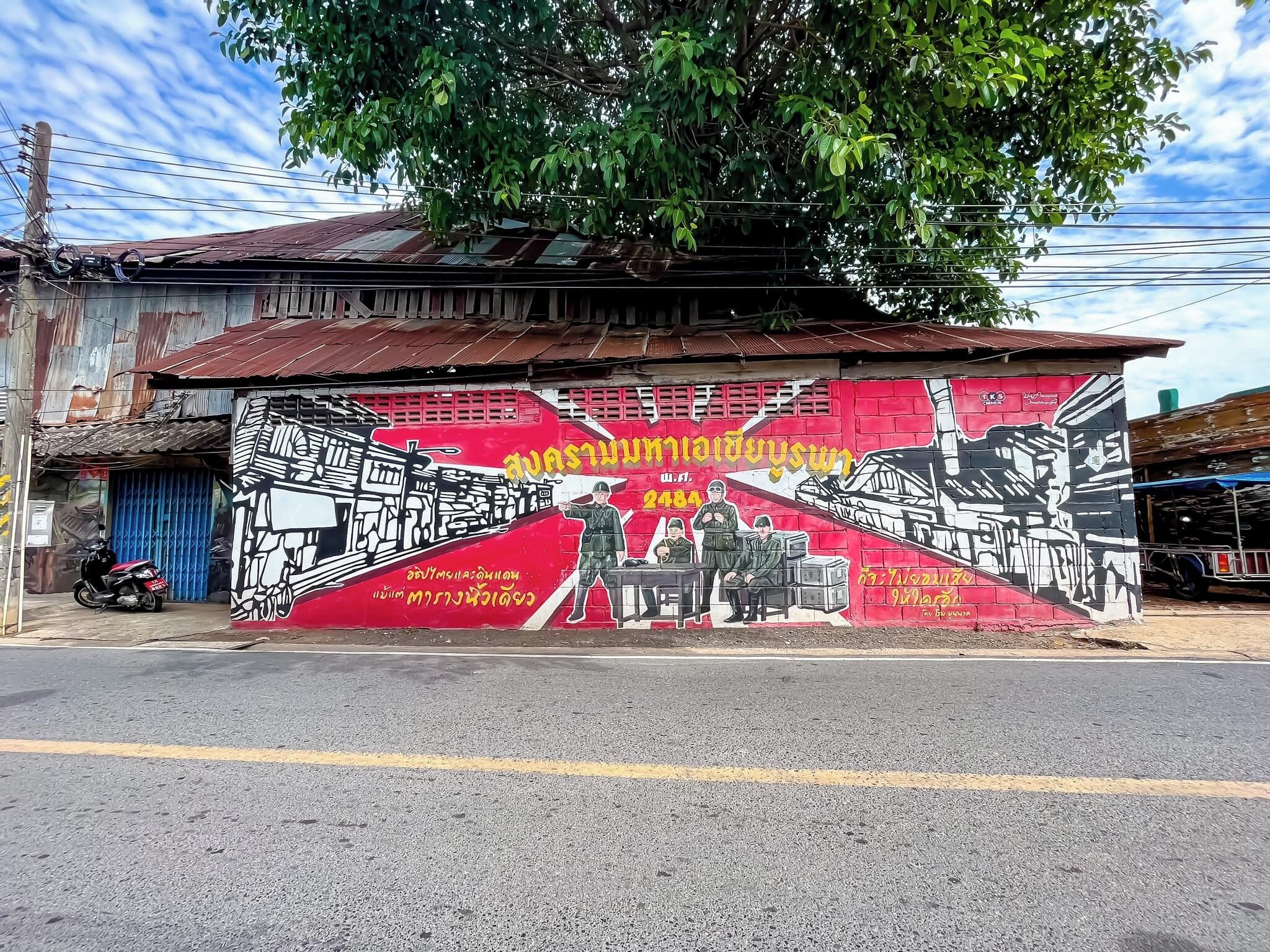 A mural on a building with a red and black color scheme, depicting soldiers and a military vehicle.