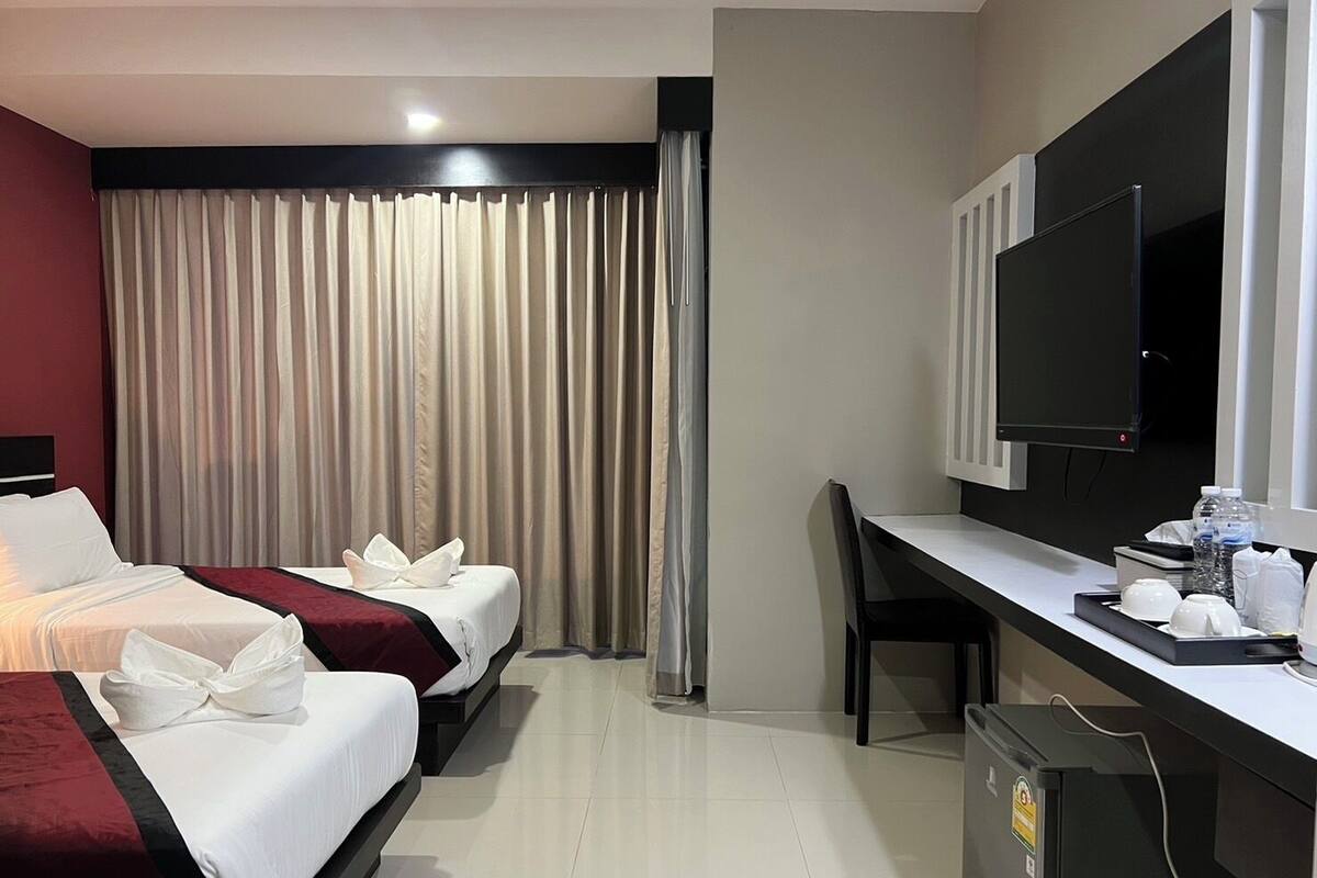 Habitación de hotel con dos camas, un escritorio, un televisor y un minibar.