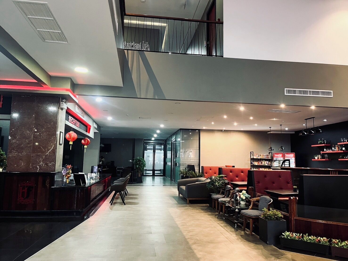 A modern hotel lobby with a reception desk, seating area, and a staircase leading to an upper level.