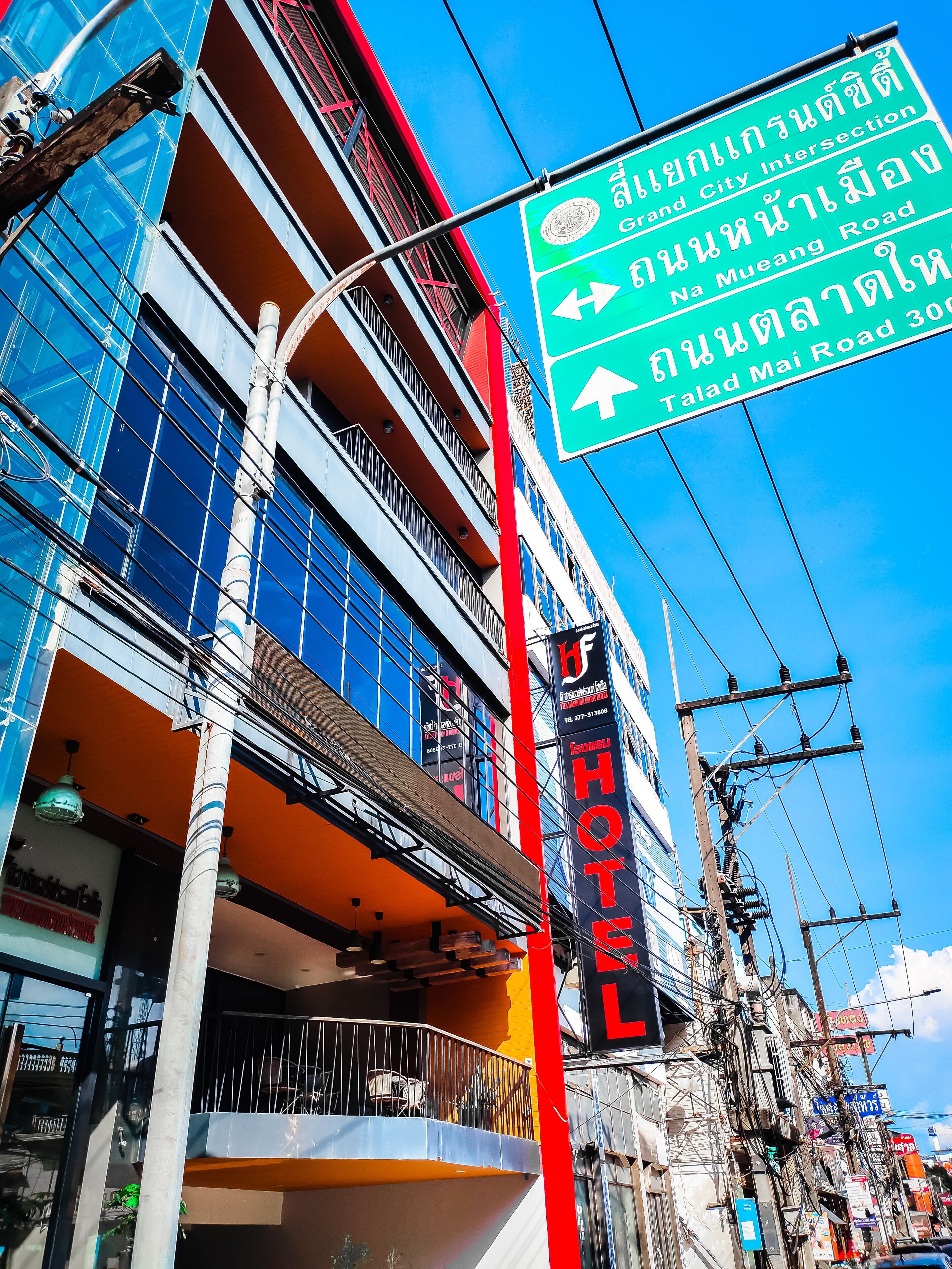 A hotel with a sign indicating directions to Grand City Intersection, Na Mueang Road, and Talad Mai Road.
