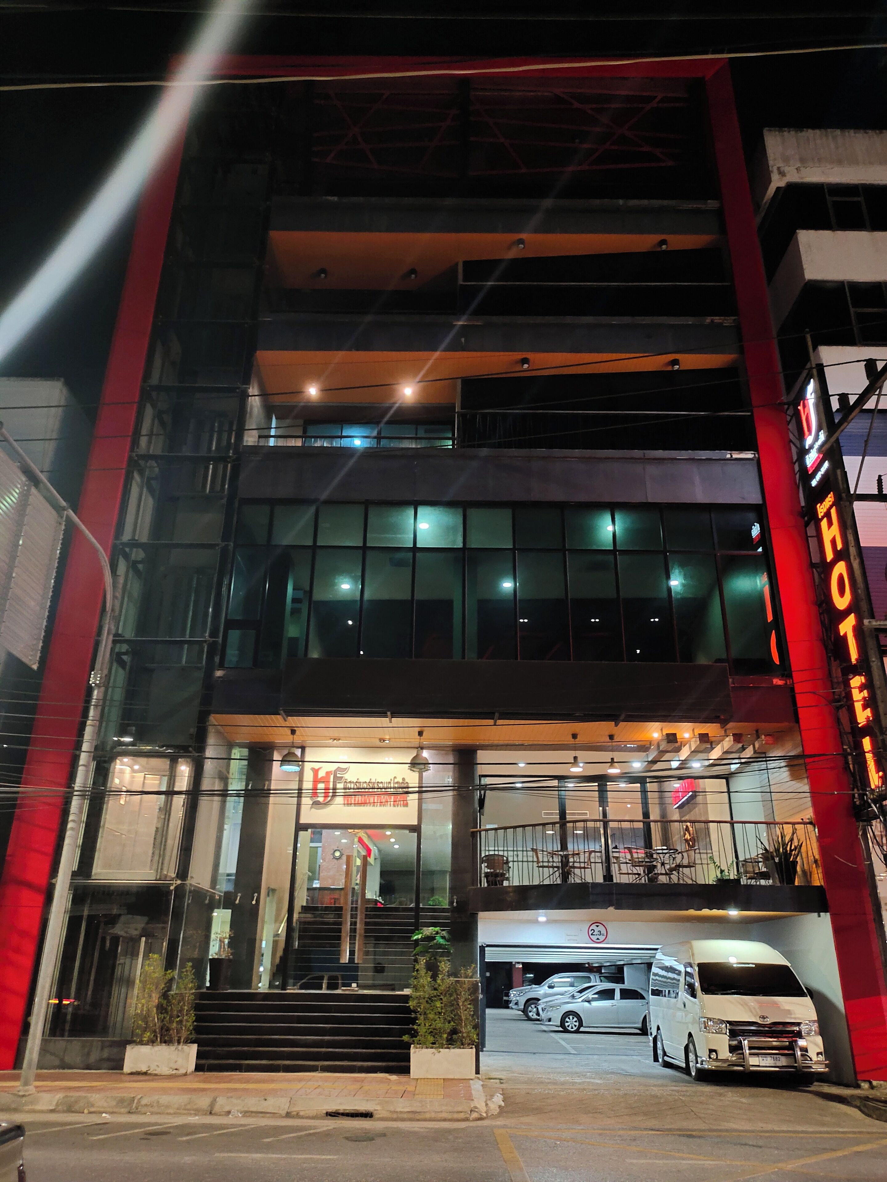 A hotel with a modern facade, large windows, and a visible entrance with a staircase leading to the entrance.