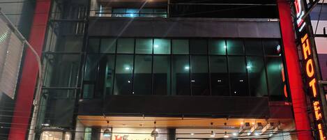 A hotel with a modern facade, large windows, and a visible entrance with a staircase leading to the entrance.