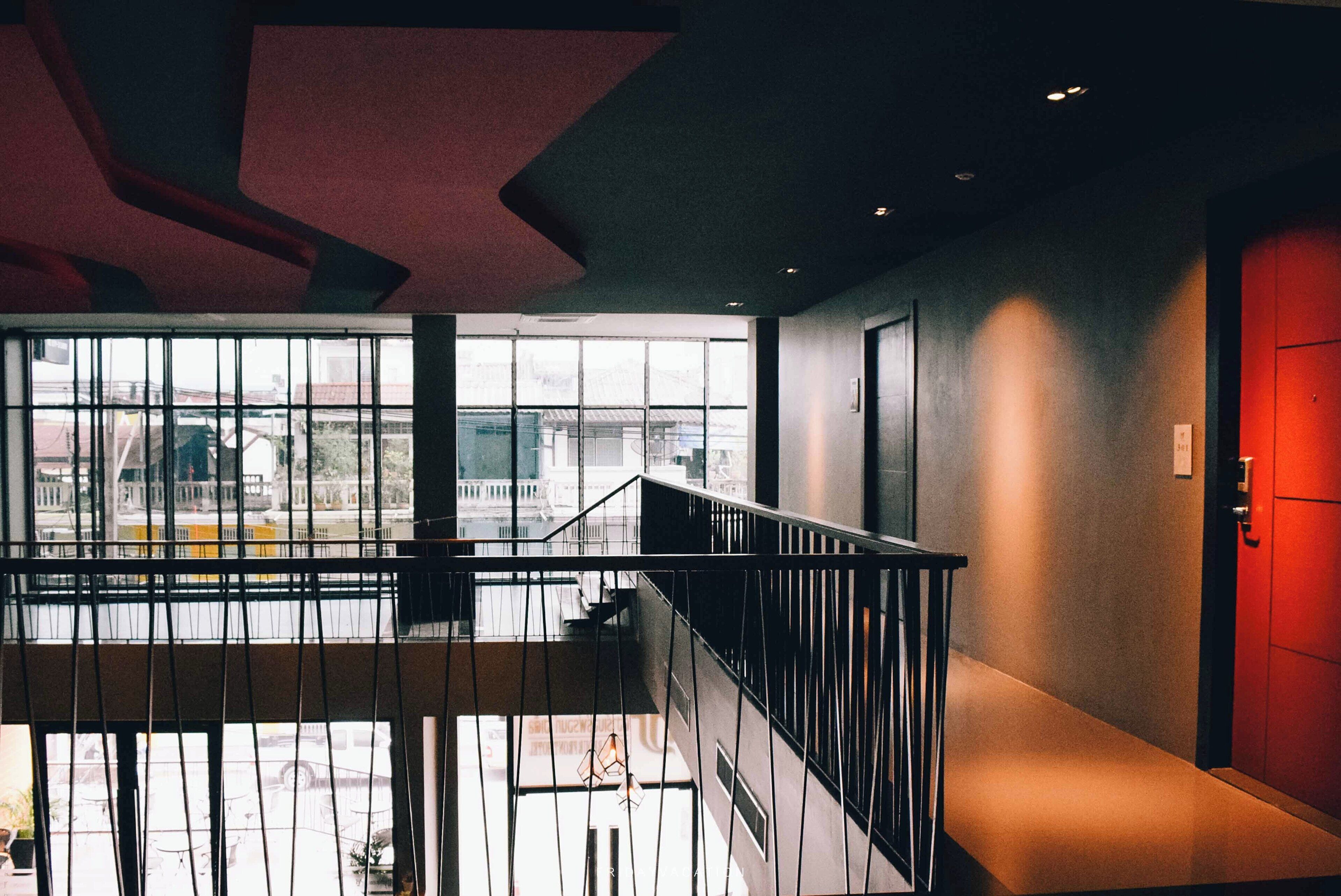 A modern interior with a staircase, large windows, and a red door.