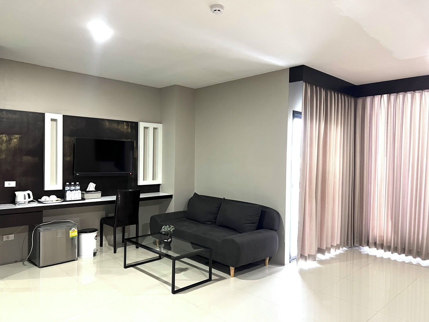 Una sala de estar moderna con un sofá, una mesa de centro, un televisor y una zona de cocina con mostrador y electrodomésticos.