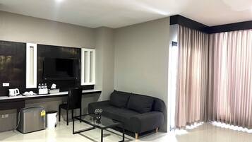 Una sala de estar moderna con un sofá, una mesa de centro, un televisor y una zona de cocina con mostrador y electrodomésticos.