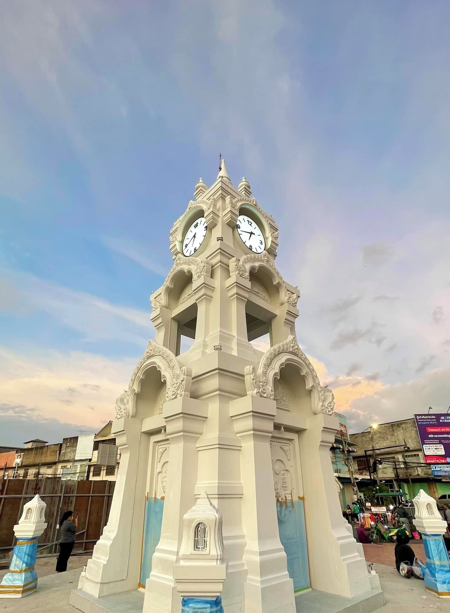 A white clock tower with two clocks, surrounded by blue and white architectural details.