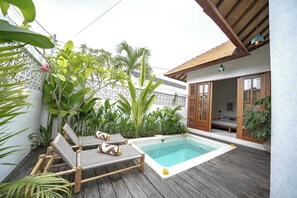 Un área de piscina con sillas de descanso y una terraza de madera.