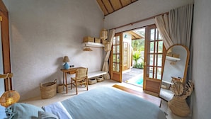 Een slaapkamer met een bed, een bureau, een stoel, een spiegel en uitzicht op het omliggende landschap.