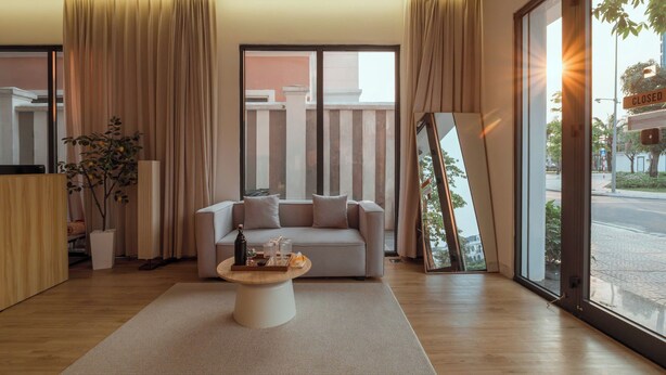 Una sala de estar moderna con un sofá, una mesa de centro y un amplio ventanal con cortinas.